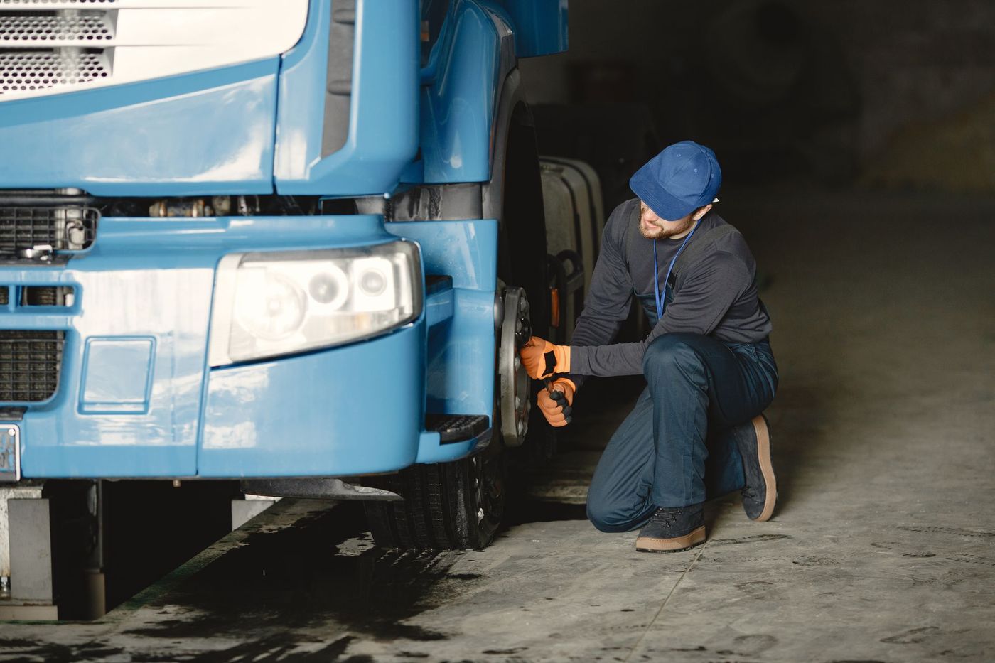 Technician working with a wrench on the front wheel of a blue truck